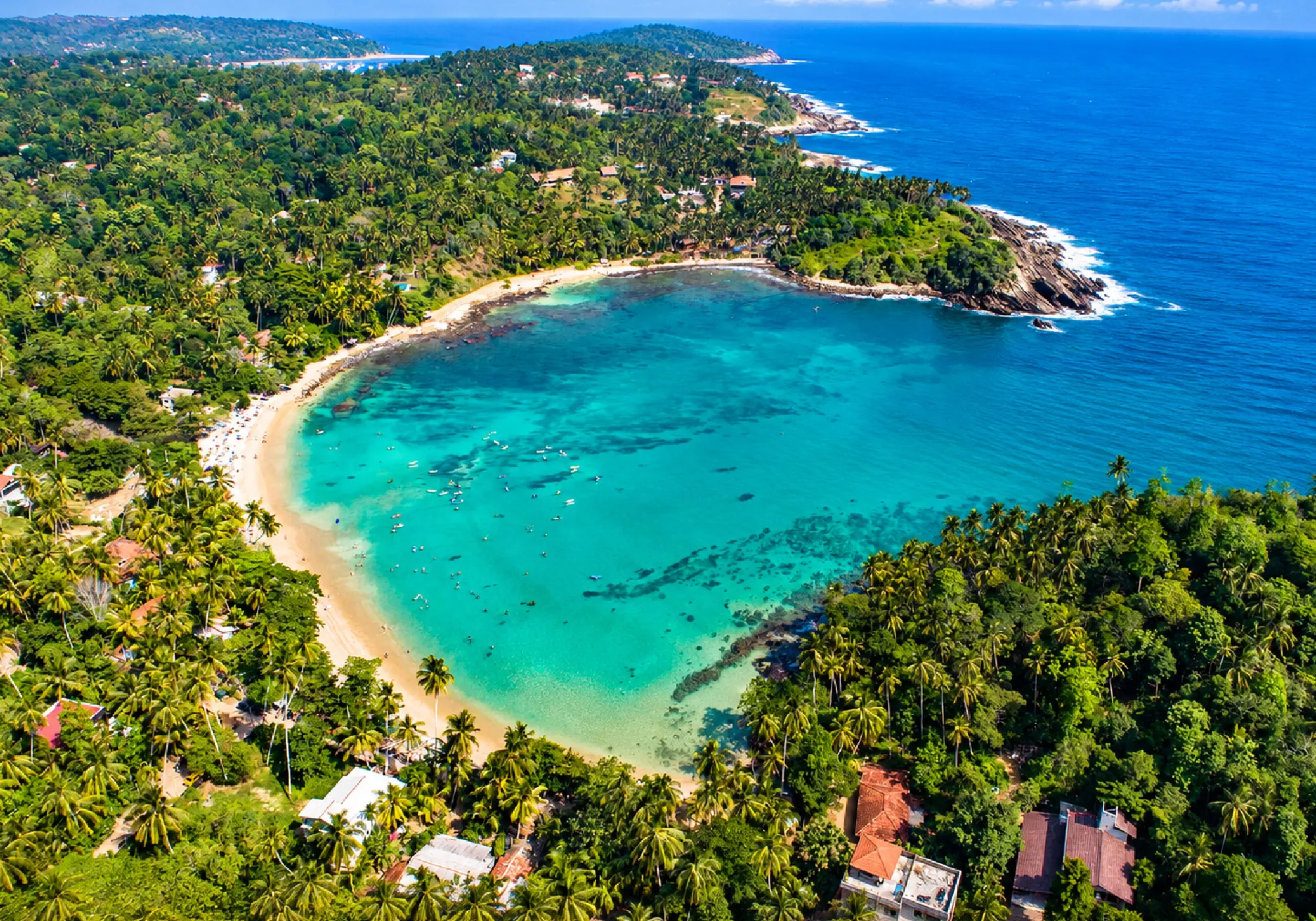 Aerial view of a tropical Sri Lankan coastline with turquoise waters, sandy beach, lush palm trees, and scenic coastal landscapes.
