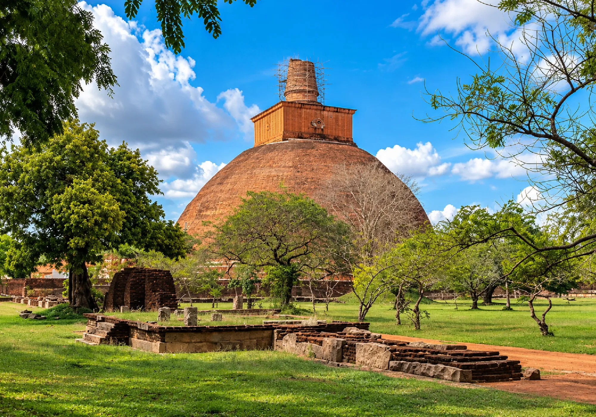 Ancient Buddhist stupa in Anuradhapura, Sri Lanka, surrounded by historic ruins and lush greenery.